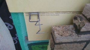 Polyextruded styrene (yellow) provides insulation between the aira nd moisture barrier (teal) and the stonework. The metal bracket is set into the grout and anchors the limestone to the wall.